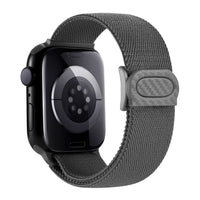 Smartwatch with a sleek black case and side button, featuring a heart rate sensor on the back and paired with a brown woven fabric band with a white loop